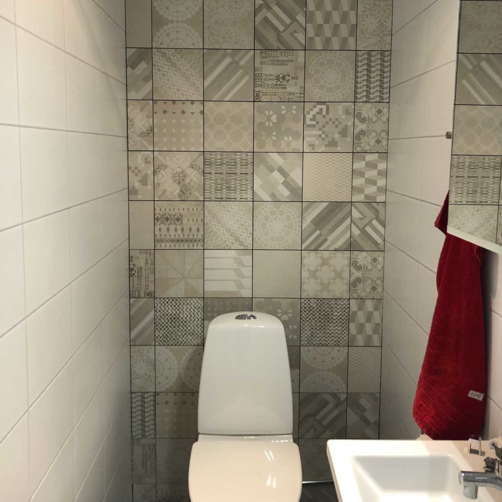 Nyrenoverad toalett med mönstrat kakel bakom toaletten, EB Golv & Kakel